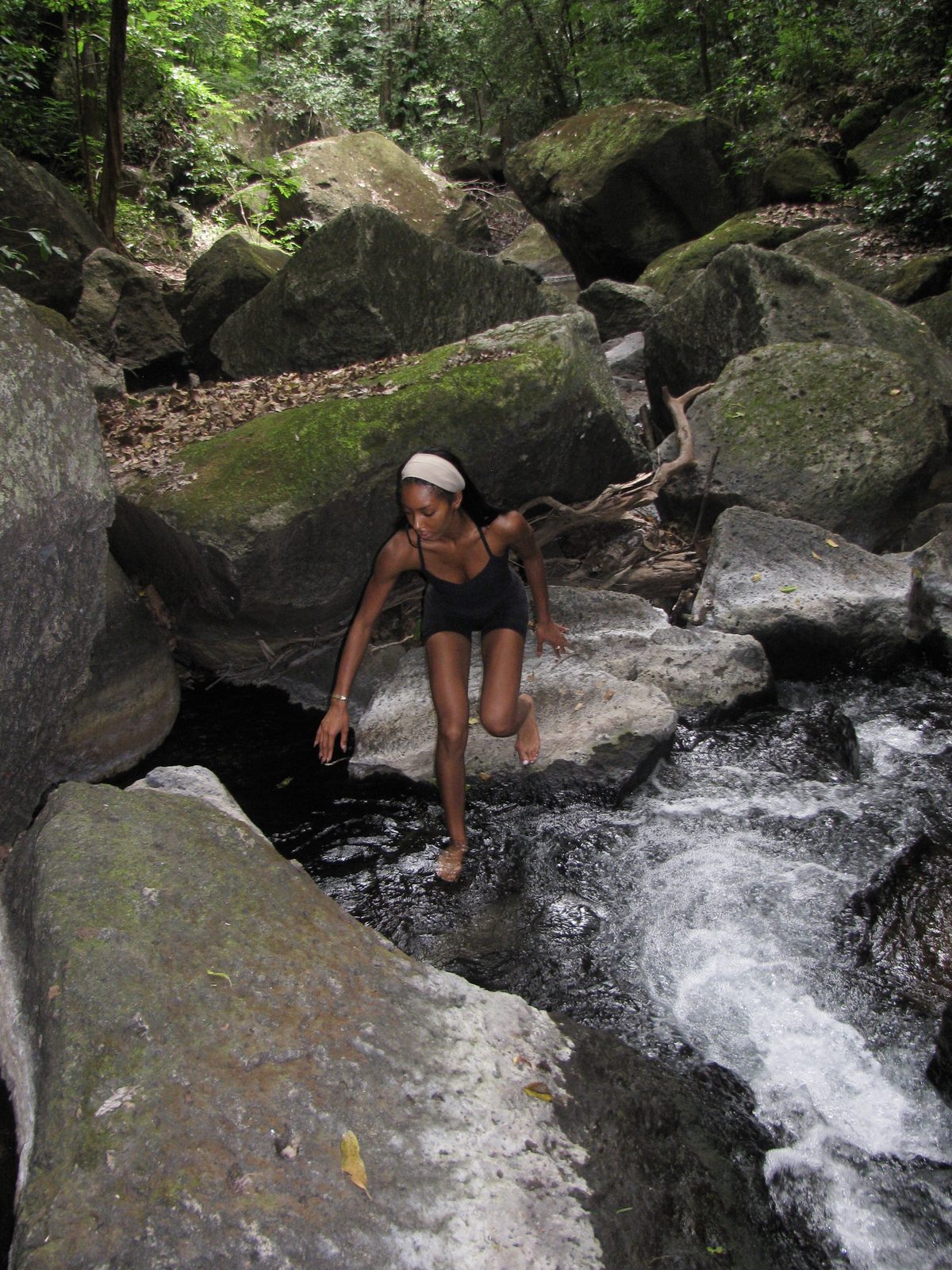 Maya crossing a forest stream over mossy stones