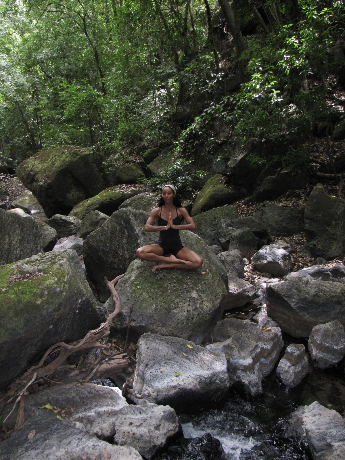 Maya meditating on moss-covered rocks beside a forest stream