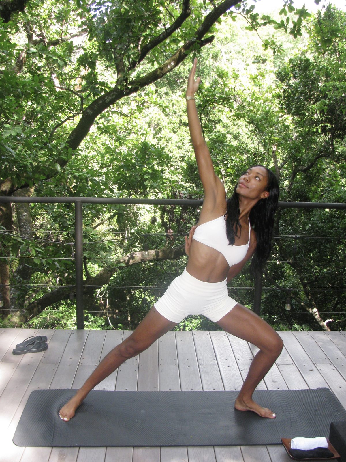 Maya in warrior pose on a deck in the forest